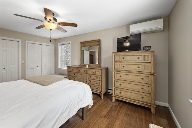 bedroom featuring a wall mounted air conditioner, dark wood-type flooring, multiple closets, and ceiling fan