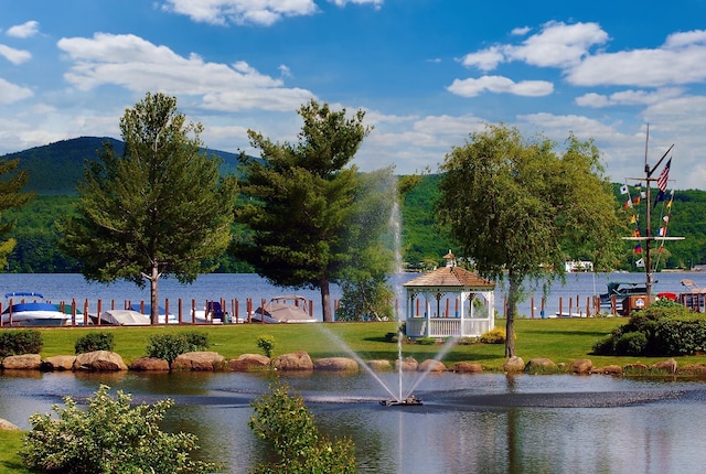 view of property's community with a water and mountain view, a yard, and a gazebo