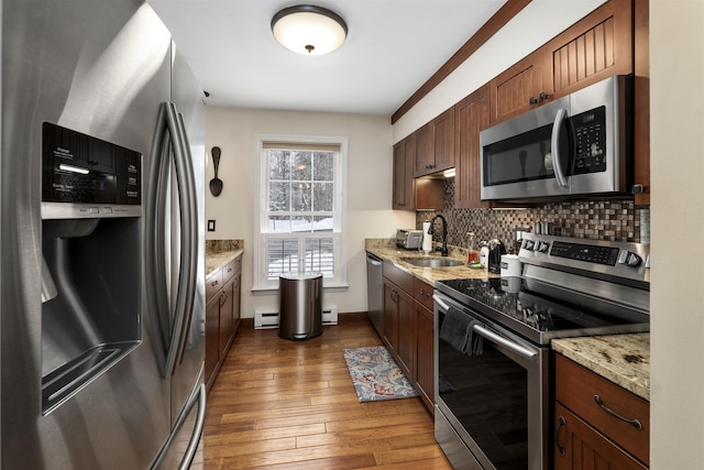 kitchen featuring dark wood-type flooring, sink, tasteful backsplash, baseboard heating, and stainless steel appliances