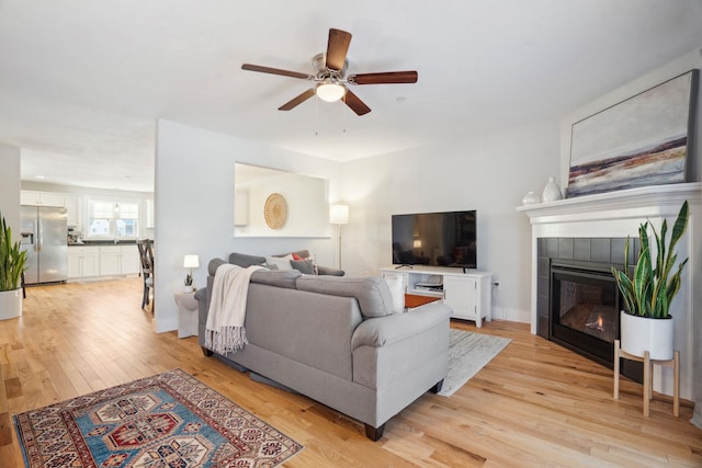 living room featuring ceiling fan, a fireplace, and light hardwood / wood-style floors