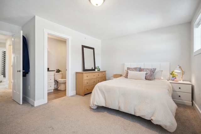 bedroom with ensuite bath and light carpet