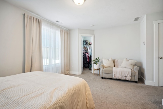 bedroom with light carpet, a walk in closet, and a closet