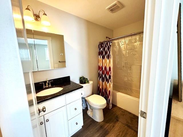 full bathroom with vanity, wood-type flooring, shower / tub combo, and toilet