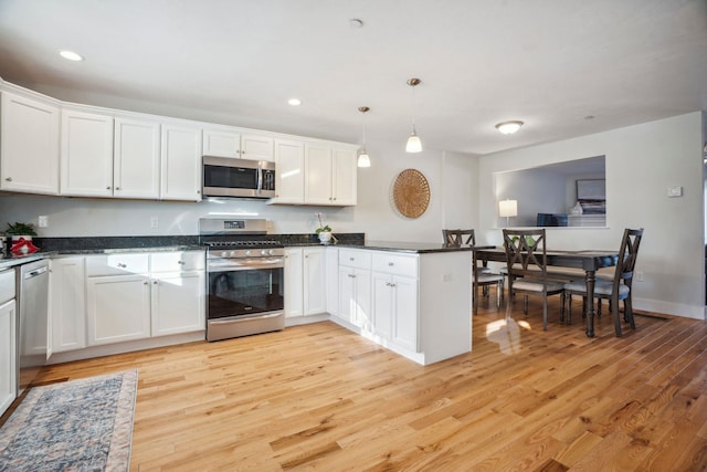 kitchen featuring white cabinetry, hanging light fixtures, kitchen peninsula, stainless steel appliances, and light wood-type flooring