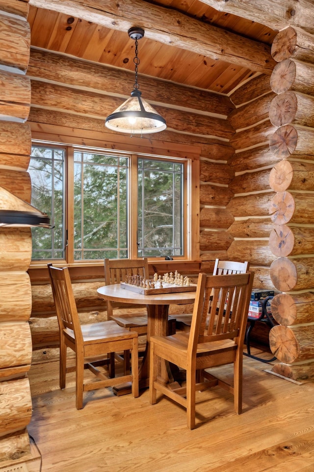 dining space featuring beam ceiling, wood ceiling, rustic walls, and light wood-type flooring