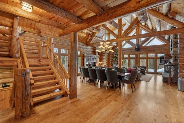 dining area with wood ceiling, rustic walls, an inviting chandelier, beamed ceiling, and light wood-type flooring