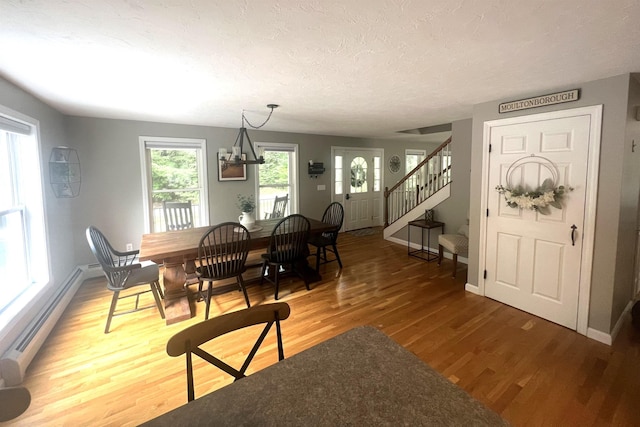 dining area featuring hardwood / wood-style flooring, a textured ceiling, and a baseboard heating unit