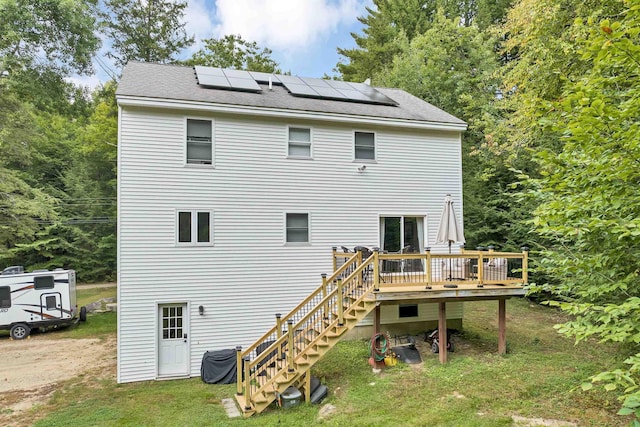 rear view of house featuring a yard, solar panels, and a deck