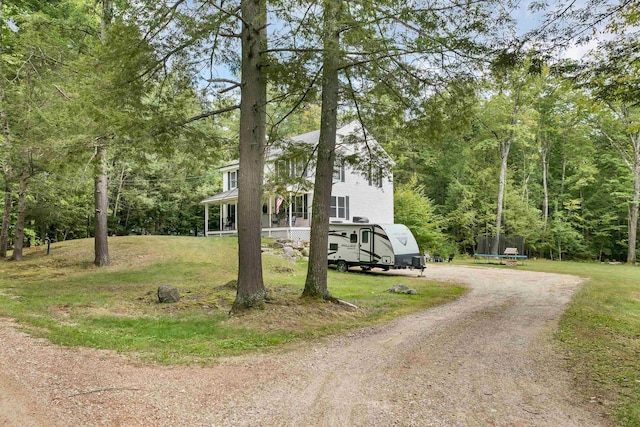 view of side of property with a trampoline, a lawn, and a porch