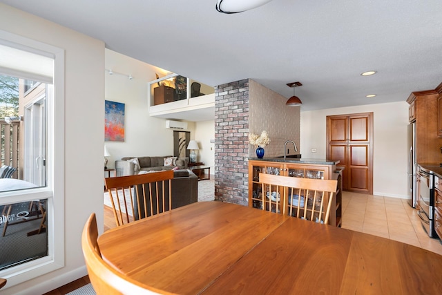 dining space featuring a wall mounted air conditioner, sink, and light tile patterned floors