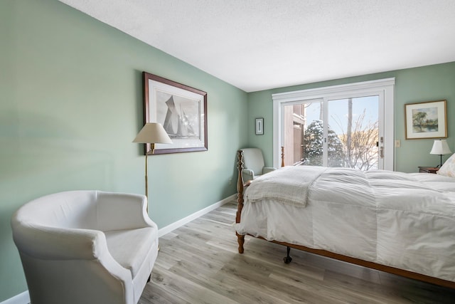 bedroom featuring access to outside, a textured ceiling, and light wood-type flooring