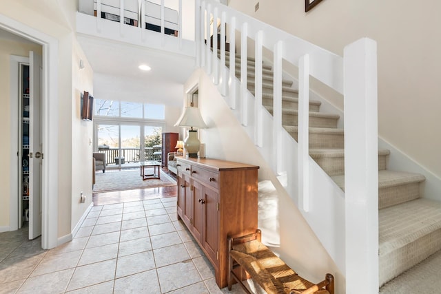 stairway with a towering ceiling and tile patterned floors