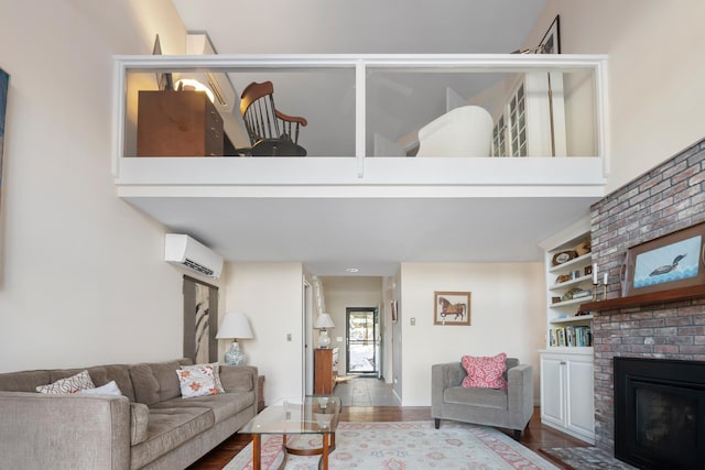 living room featuring hardwood / wood-style flooring, a towering ceiling, a fireplace, and a wall mounted AC