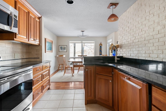 kitchen featuring light tile patterned floors, sink, hanging light fixtures, stainless steel appliances, and tasteful backsplash