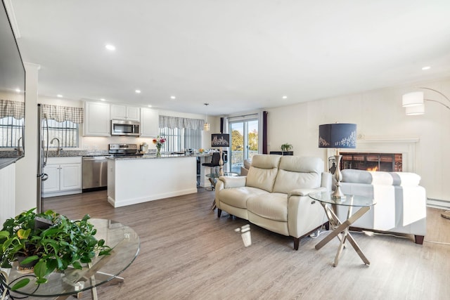 living room with a brick fireplace and light wood-type flooring