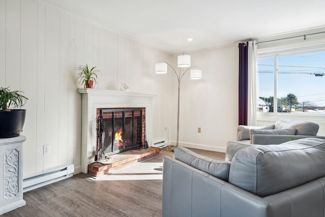 living room featuring hardwood / wood-style flooring, a fireplace, crown molding, and a baseboard heating unit