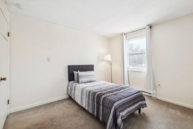 bedroom with light colored carpet and a baseboard heating unit