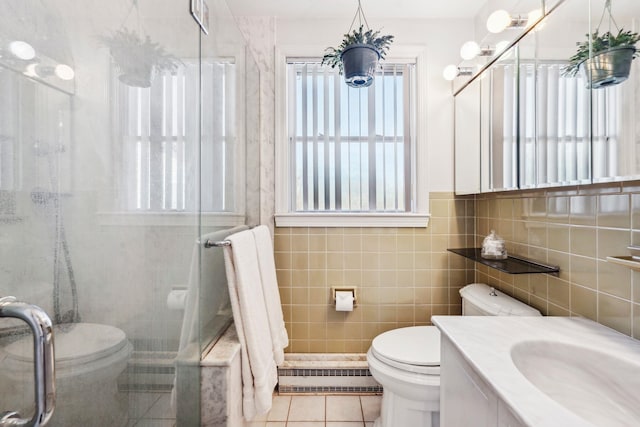 bathroom featuring toilet, a shower with shower door, tile patterned flooring, and tile walls