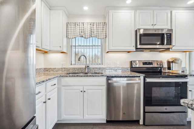 kitchen featuring stainless steel appliances, white cabinetry, light stone countertops, and sink