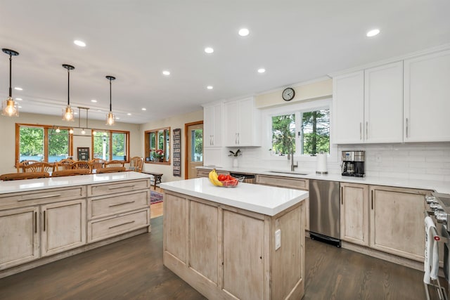 kitchen featuring sink, appliances with stainless steel finishes, a kitchen island, decorative light fixtures, and light brown cabinets