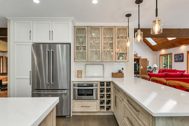 kitchen featuring pendant lighting, lofted ceiling with skylight, stainless steel appliances, dark hardwood / wood-style floors, and decorative backsplash