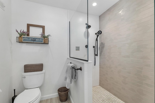 bathroom with a tile shower and toilet