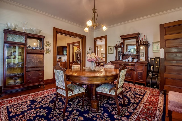 dining space with crown molding, dark wood-type flooring, and a chandelier