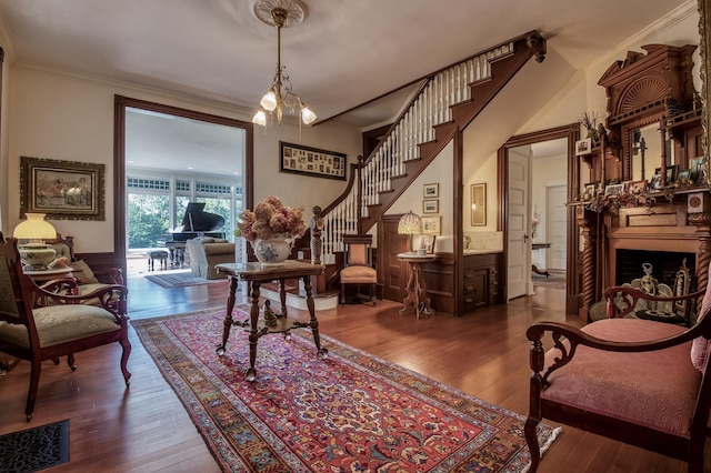 living area featuring ornamental molding, dark wood-type flooring, and a notable chandelier