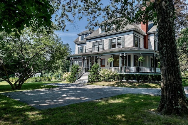 victorian-style house featuring a porch and a front yard