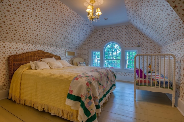 bedroom featuring vaulted ceiling, hardwood / wood-style floors, and a notable chandelier