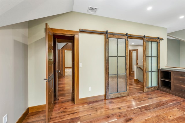 interior space featuring lofted ceiling, wood-type flooring, and a barn door