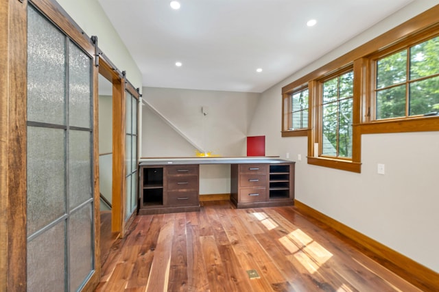 bar with light hardwood / wood-style flooring, built in desk, and a barn door