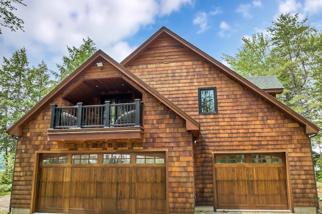 log-style house featuring a garage and a balcony