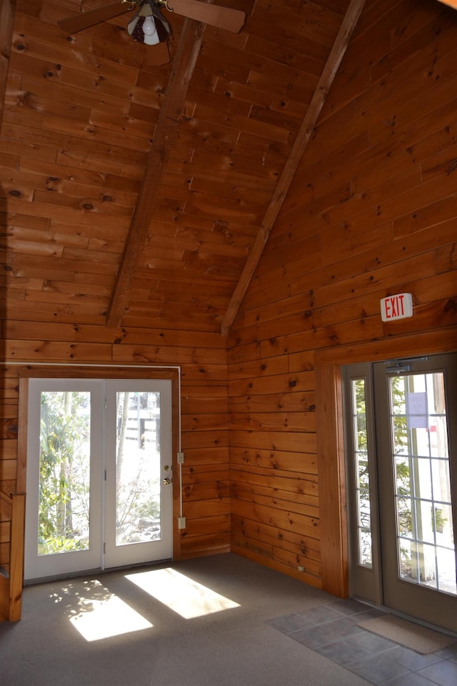 unfurnished living room with beam ceiling, high vaulted ceiling, wooden ceiling, and wooden walls