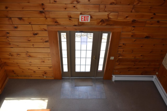 doorway to outside with wood walls, a healthy amount of sunlight, and a baseboard heating unit