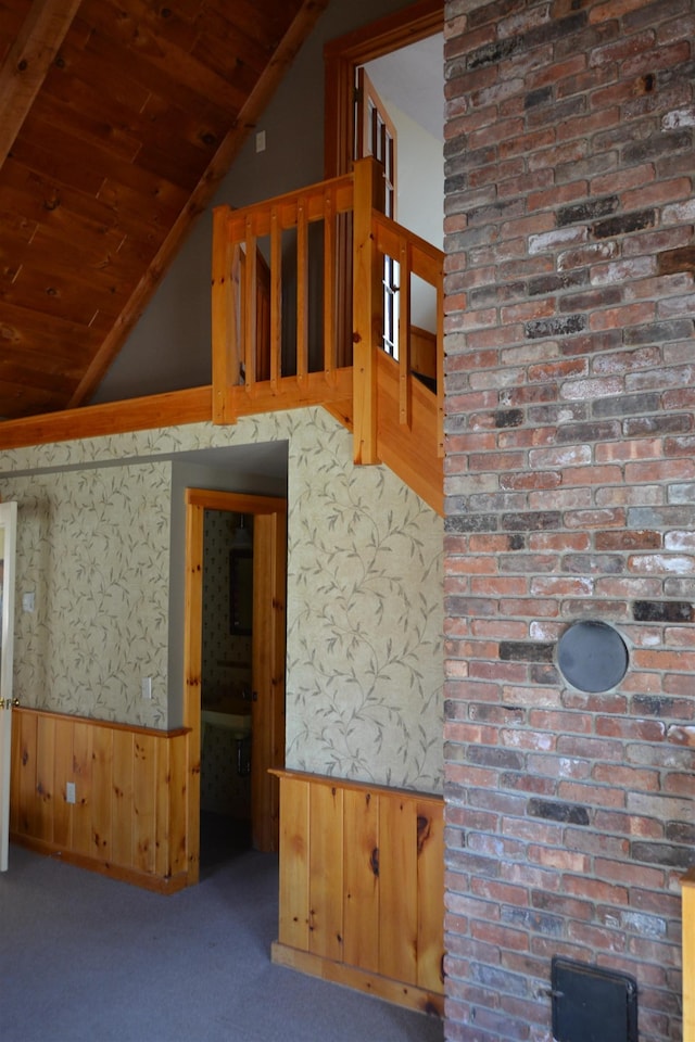 unfurnished living room featuring lofted ceiling, wooden walls, wooden ceiling, and carpet