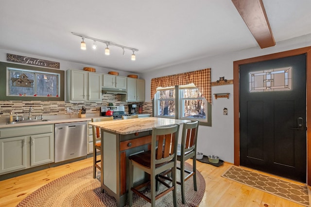 kitchen with dishwasher, sink, backsplash, a kitchen bar, and light wood-type flooring