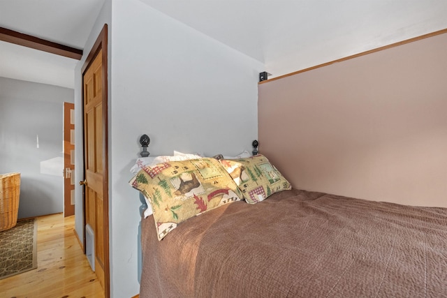 bedroom featuring beamed ceiling, light hardwood / wood-style floors, and a closet