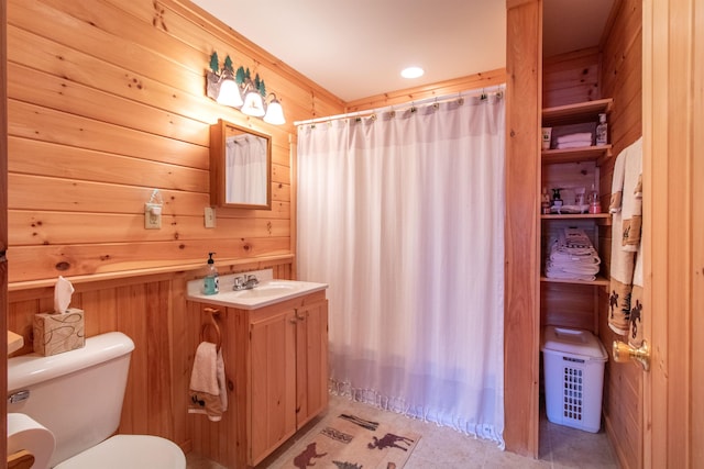 bathroom featuring vanity, tile patterned flooring, wooden walls, and toilet