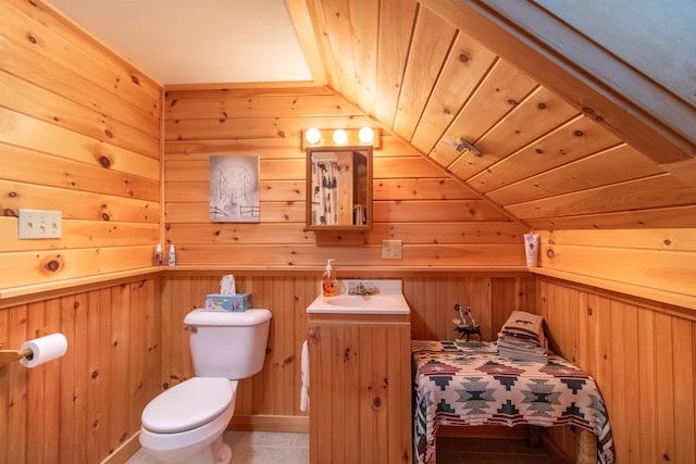 bathroom featuring wood walls, vanity, tile patterned floors, and toilet