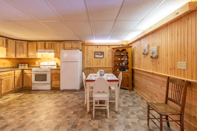 kitchen featuring a drop ceiling, sink, white appliances, and wooden walls