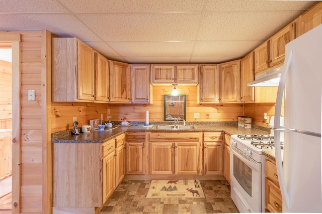 kitchen with sink, white appliances, a paneled ceiling, and wood walls