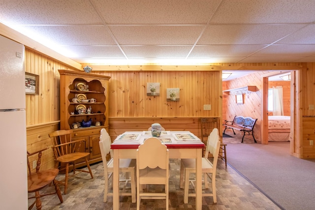 dining area with a drop ceiling and wood walls