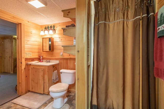 bathroom with vanity, a paneled ceiling, wooden walls, and toilet