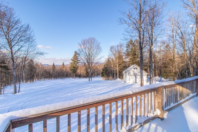 snow covered deck with a garage and an outdoor structure