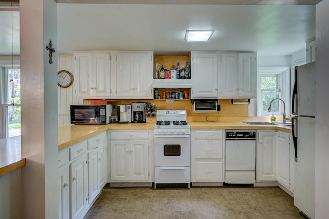 kitchen with white cabinetry, sink, and white appliances