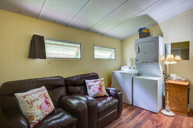 laundry area with stacked washer / drying machine and dark hardwood / wood-style floors