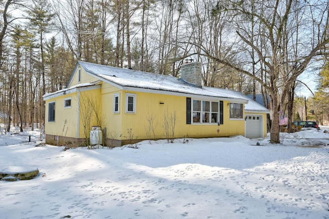 snow covered back of property with a garage