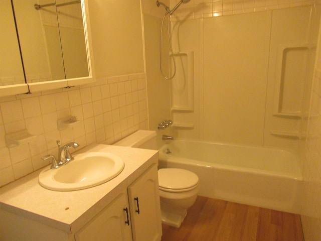 full bathroom with shower / tub combination, tile walls, hardwood / wood-style floors, vanity, and toilet