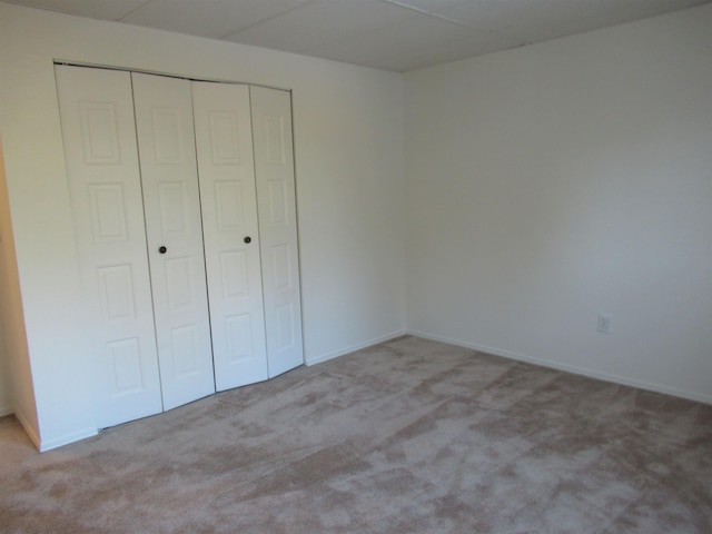 unfurnished bedroom with light carpet and a closet